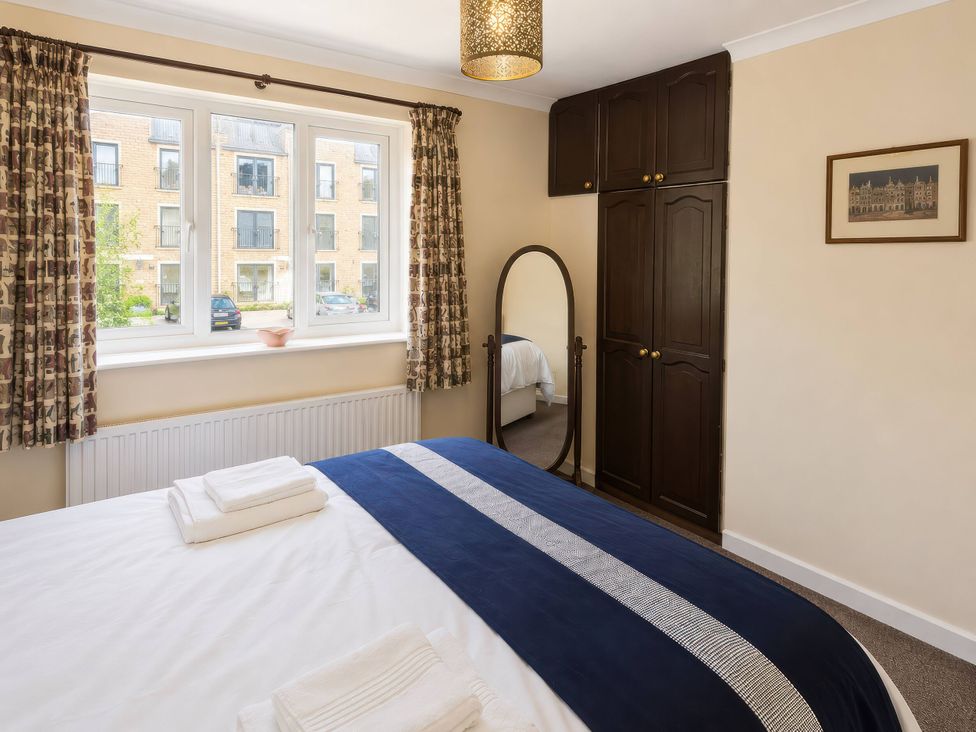 A bedroom with a bed and mirror at Beckside Cottage in Hebden Bridge