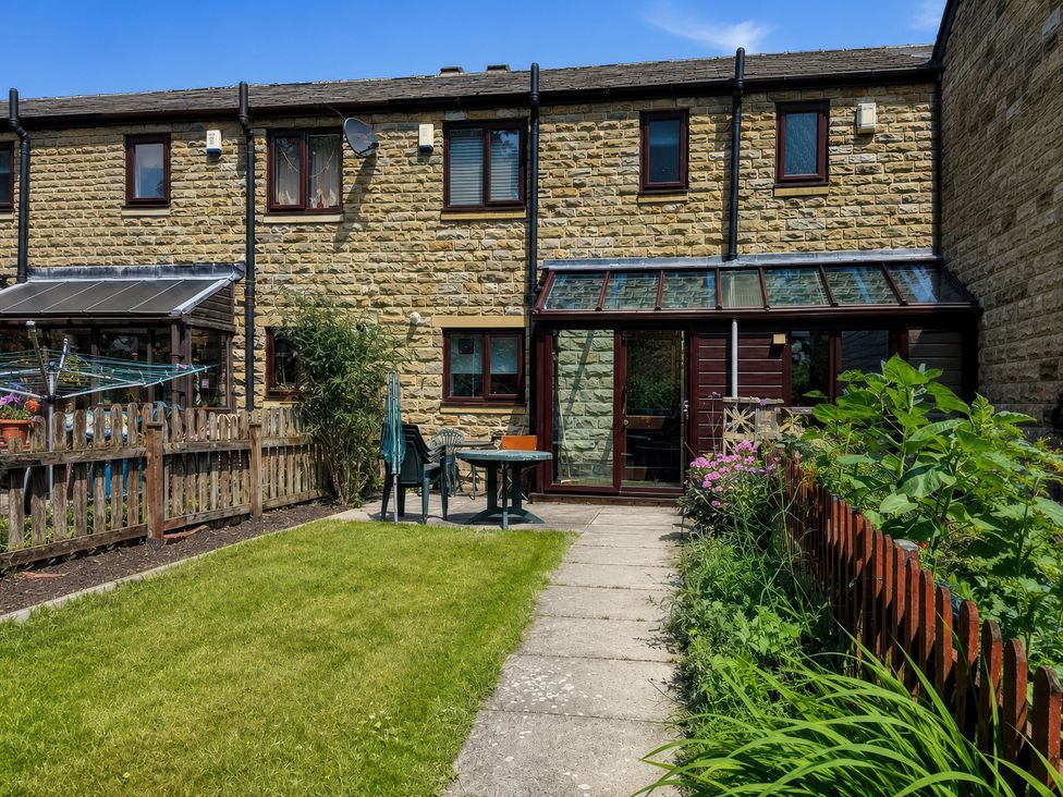 A garden with a house and seating area at Beckside Cottage Hebden Bridge