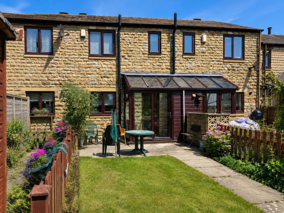 A garden with a table and chairs at Beckside Cottage in Hebden Bridge