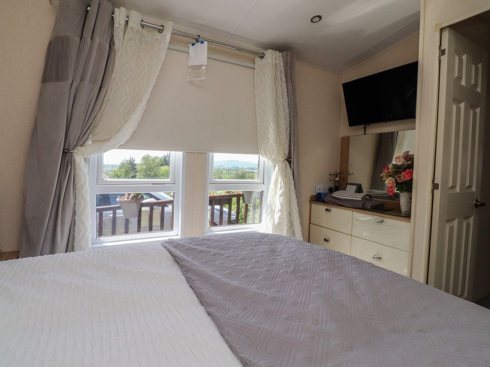 A bedroom with a bed and windows at 33 Pendle View Clitheroe