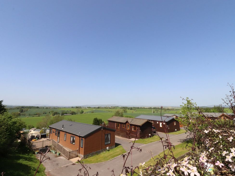 A view of cabins with a grassy area and trees at 33 Pendle View in Clitheroe