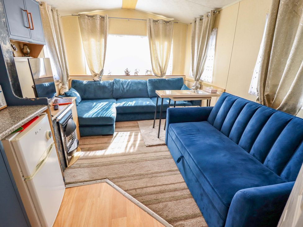 A living room with blue sofas and a table at 517 - Promenade Caravan Site in Skegness