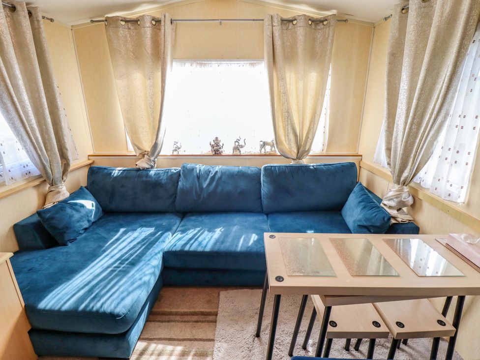 A living room with a blue sofa and a dining table at 517 - Promenade Caravan Site in Skegness