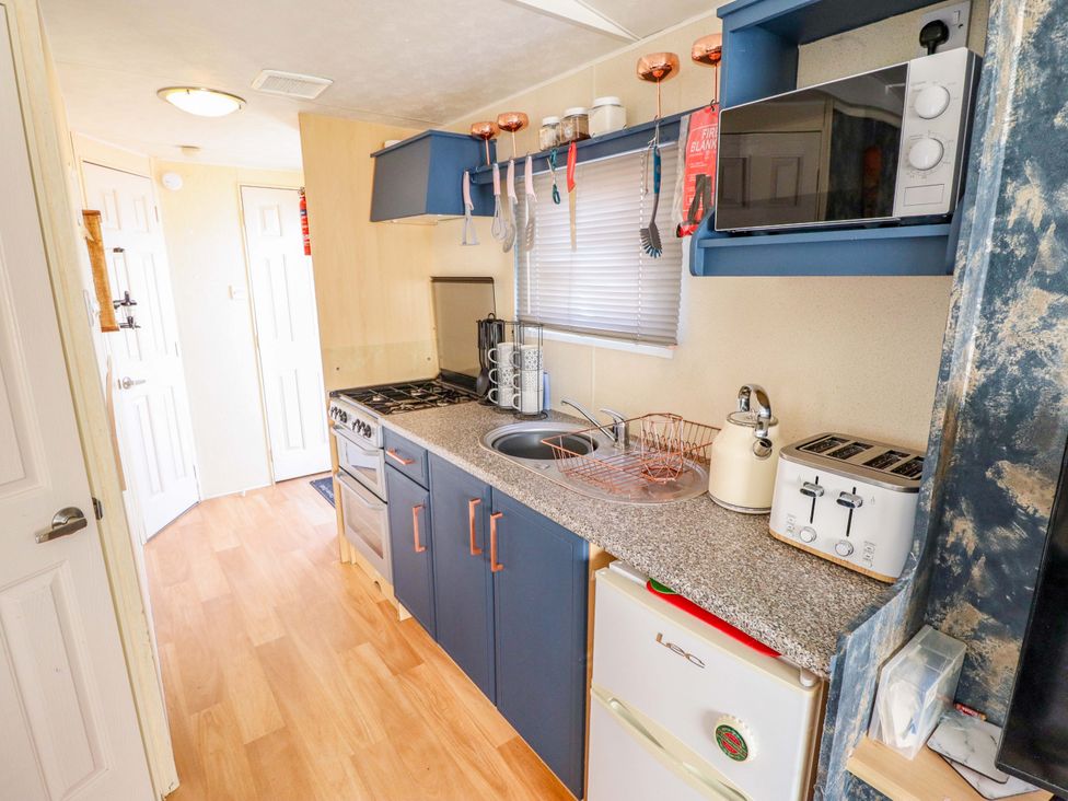 A kitchen with stove, sink, and microwave at 517 - Promenade Caravan Site in Skegness