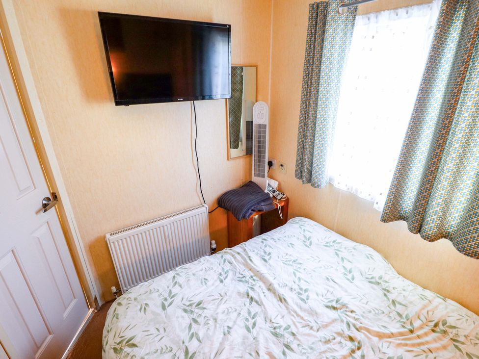 A bedroom with a bed and television at 517 - Promenade Caravan Site Skegness