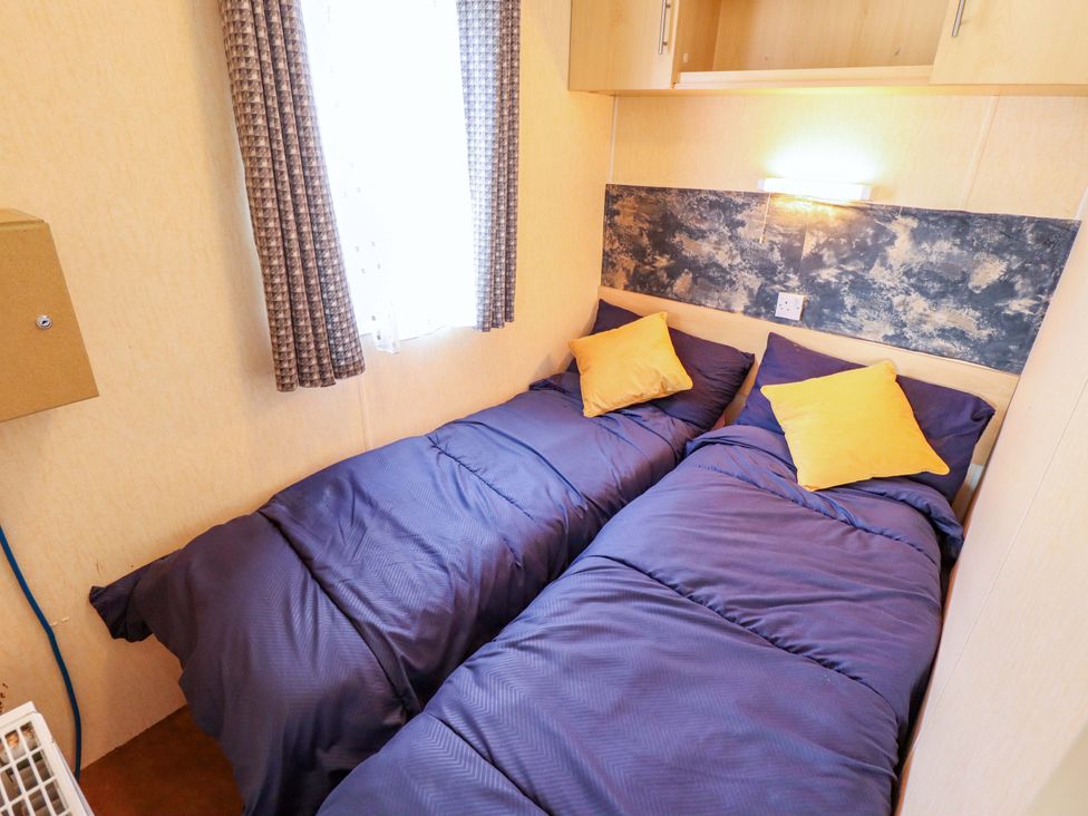 A bedroom with two beds and a window at 517 - Promenade Caravan Site in Skegness