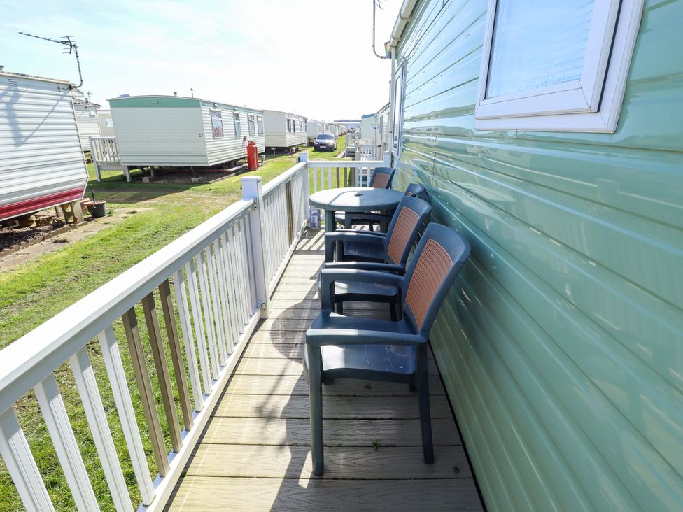 A deck area with chairs and a table at 517 - Promenade Caravan Site in Skegness