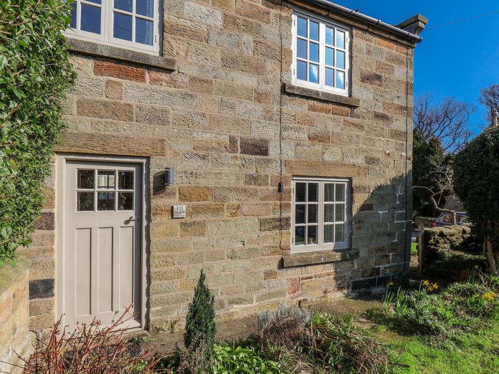A stone cottage exterior with windows and a door at Holly Cottage in Whitby