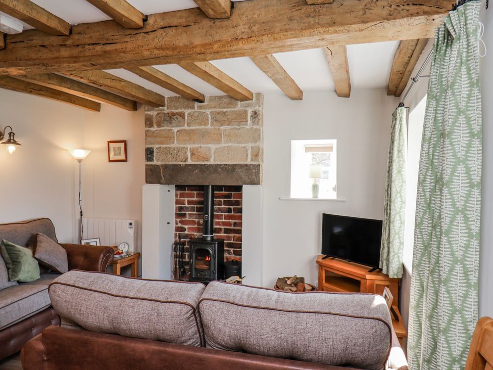A living room with a fireplace and sofa at Holly Cottage in Whitby