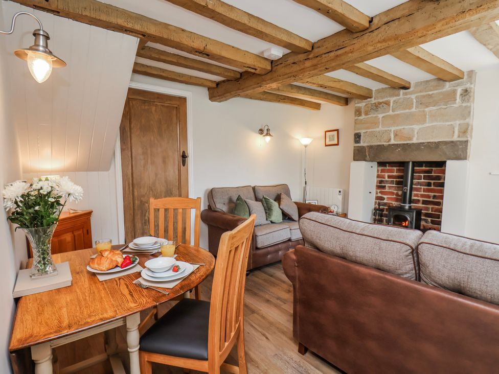 A living room with a wooden table and chairs at Holly Cottage in Whitby