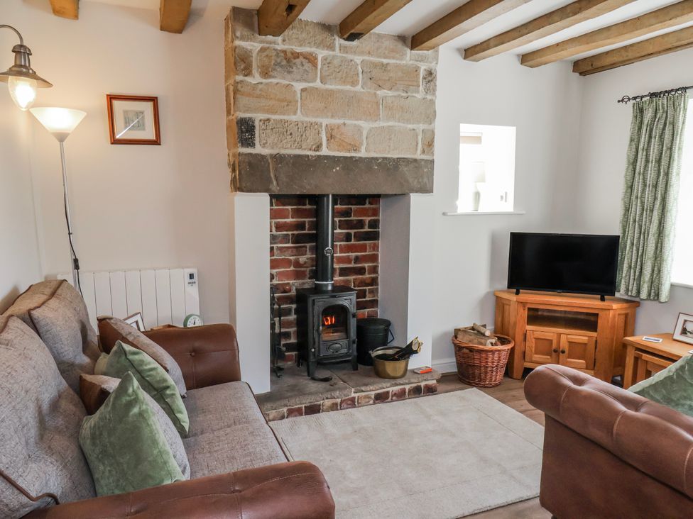 A living room with a wood stove and sofa at Holly Cottage in Whitby