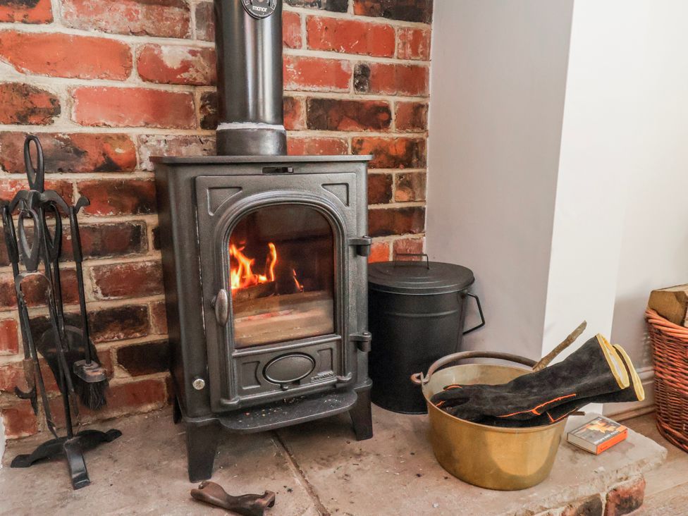 A stove with firewood and tools in a living room at Holly Cottage in Whitby
