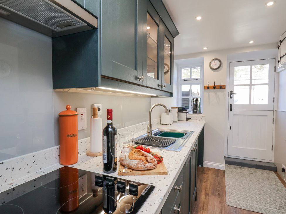A kitchen with a sink and wine bottle at Holly Cottage in Whitby