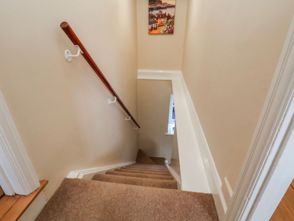 A staircase with a handrail and a picture on the wall at Holly Cottage in Whitby