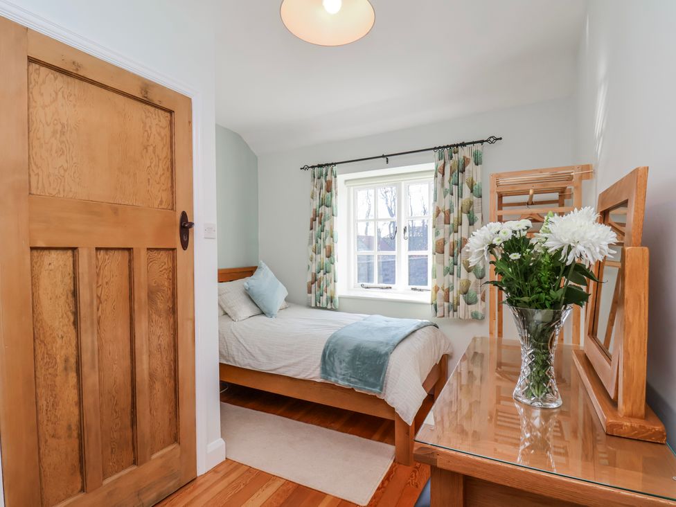 A bedroom with a bed and curtains at Holly Cottage in Whitby