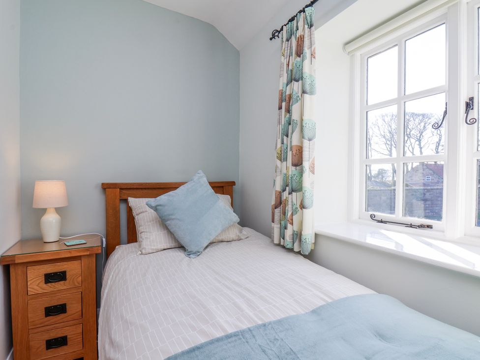 A bedroom with a single bed and a bedside table at Holly Cottage in Whitby