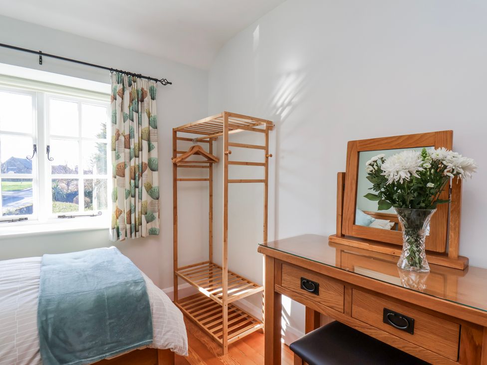 A bedroom with a mirror and a coat rack at Holly Cottage in Whitby