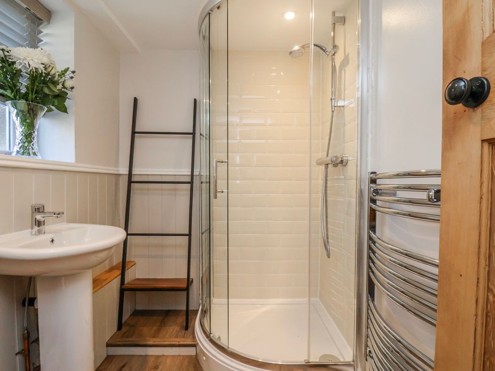 A bathroom with a shower, sink, and towel warmer at Holly Cottage in Whitby