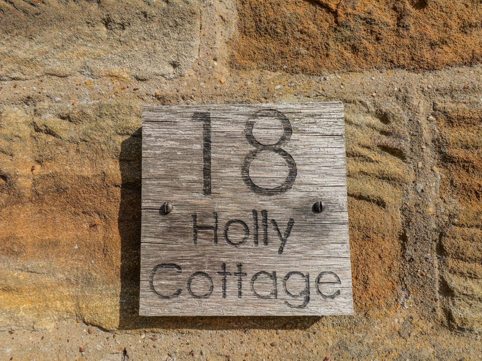 A wooden house sign with number 18 and name Holly Cottage at Holly Cottage in Whitby