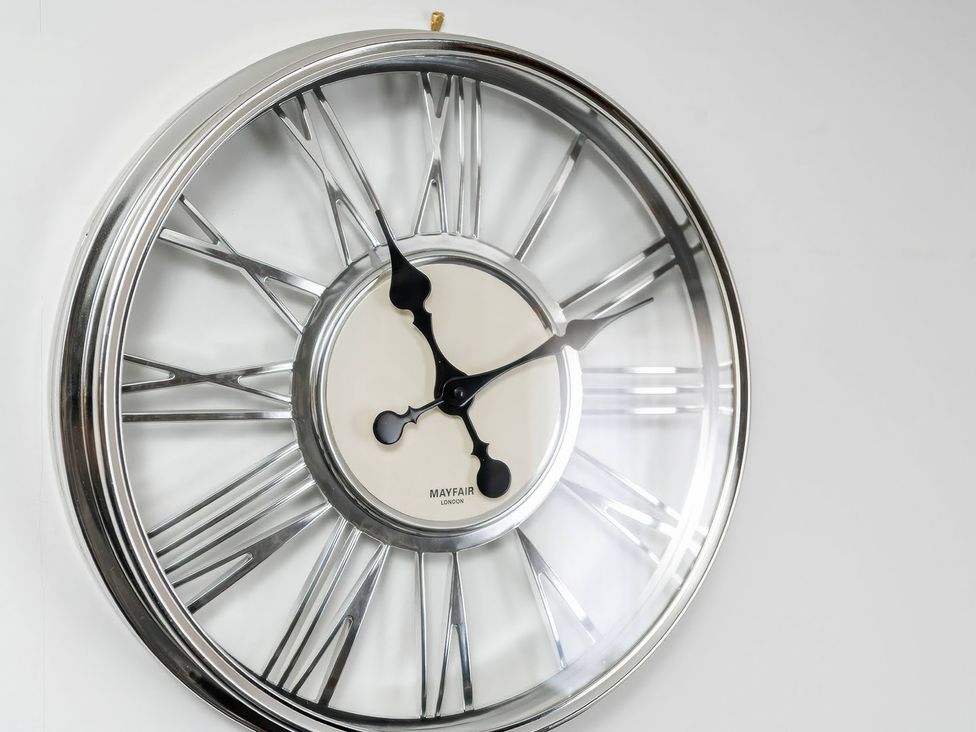 A wall clock with a silver frame and black hands at 59 Eagle Drive in Grimsby