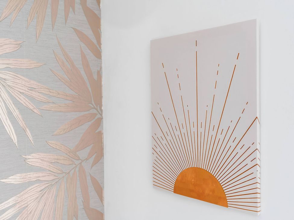 A wall with a tropical wallpaper and sun motif wall art at 59 Eagle Drive in Grimsby