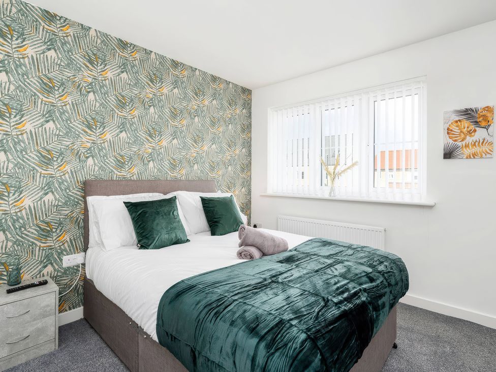 A bedroom with a bed and decorative wallpaper at 59 Eagle Drive in Grimsby