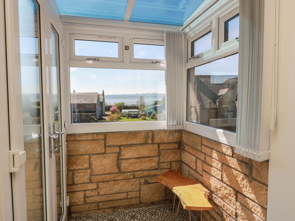 A conservatory with stone walls and a bench at Crown Cottage in Newmills near Cairneyhill