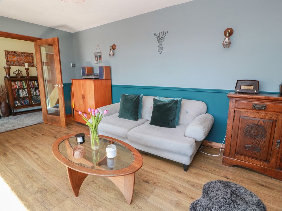 A living room with a couch, coffee table, and bookshelf at Crown Cottage Newmills near Cairneyhill