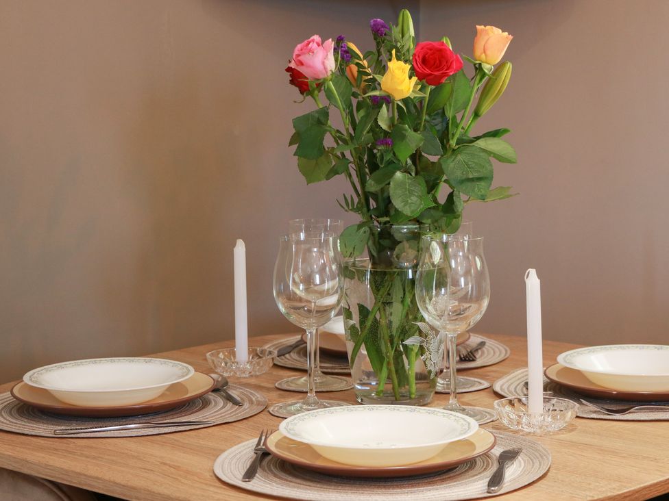 A dining table with plates and a flower vase at Crown Cottage Newmills near Cairneyhill