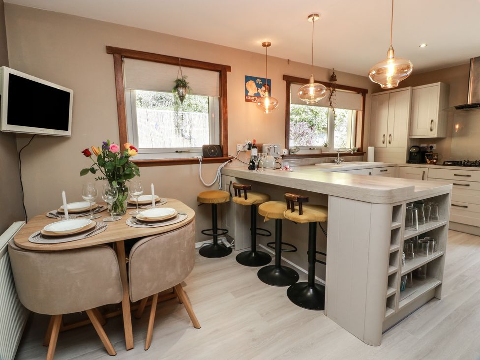 A kitchen with a dining table and stools at Crown Cottage in Newmills near Cairneyhill