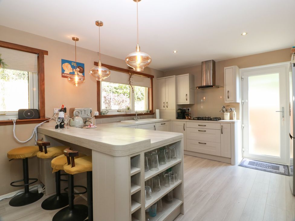 A kitchen with a stove and bar stools at Crown Cottage Newmills near Cairneyhill