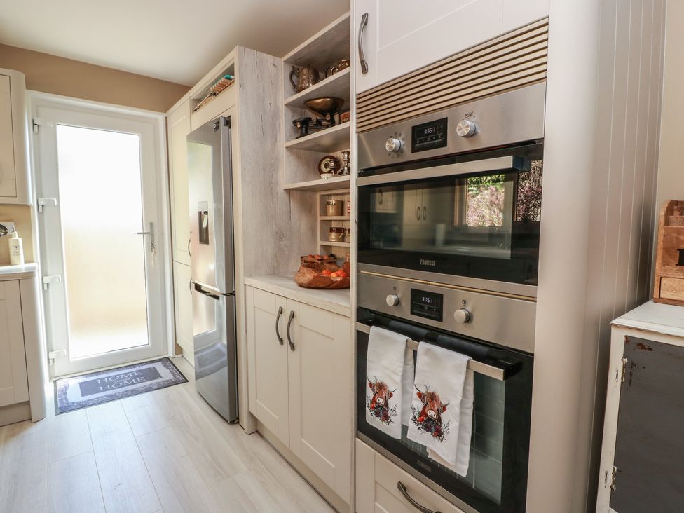 A kitchen with appliances and a door at Crown Cottage in Newmills near Cairneyhill