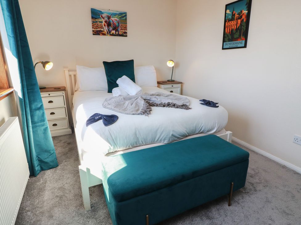 A bedroom with a bed and bedside lamp at Crown Cottage in Newmills near Cairneyhill