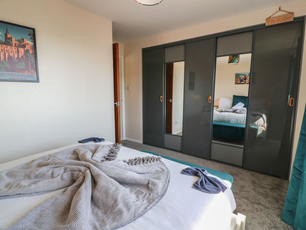 A bedroom with a bed and wardrobe at Crown Cottage in Newmills near Cairneyhill