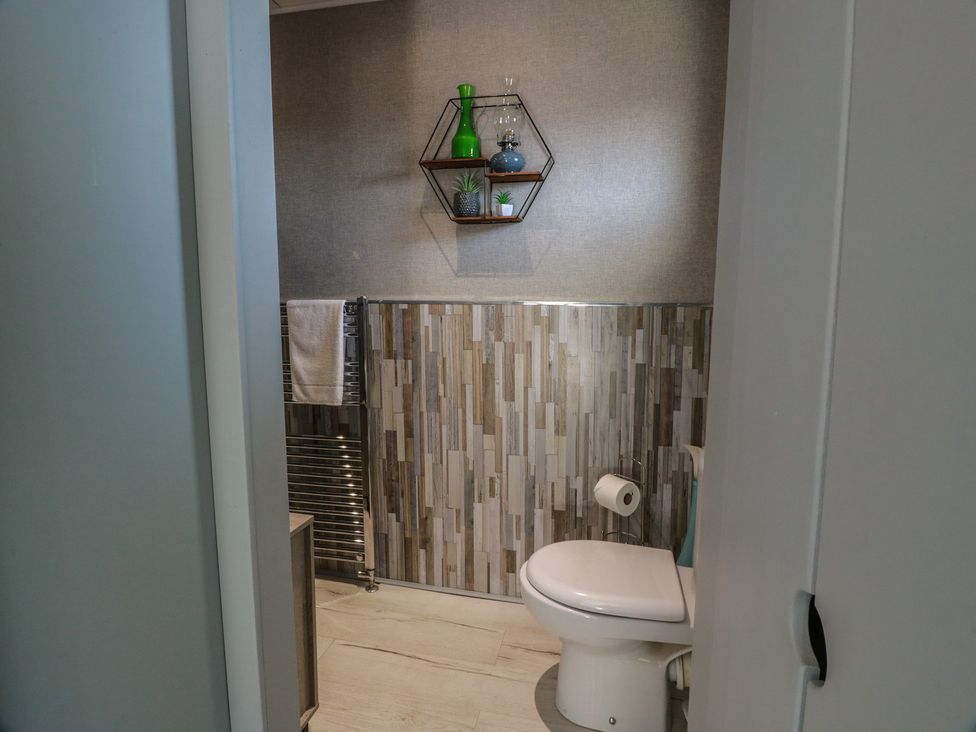 A bathroom with a toilet and wall shelf at Crown Cottage near Cairneyhill