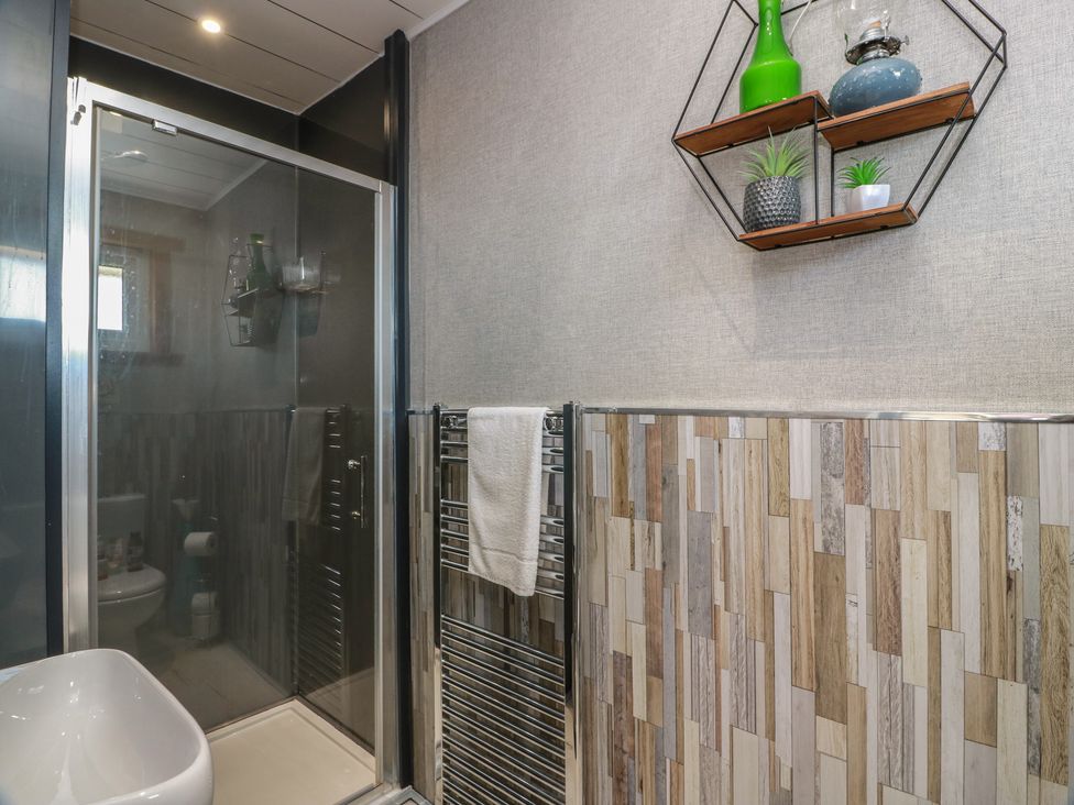 A bathroom with a shower and a towel rack at Crown Cottage in Newmills near Cairneyhill