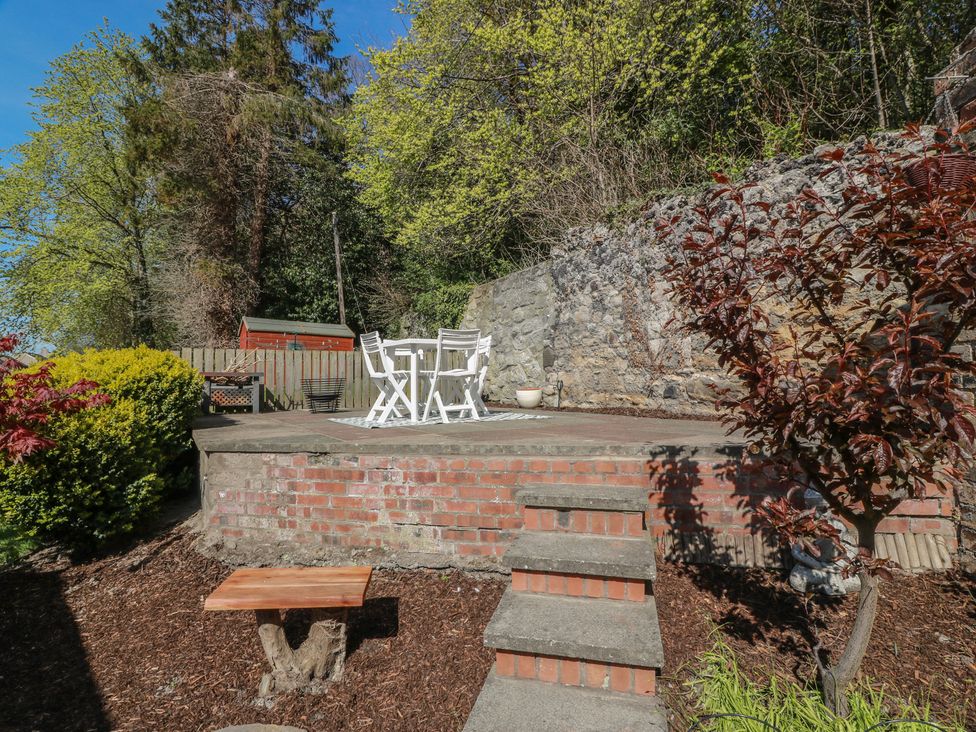 A garden with a patio area featuring a table and chairs at Crown Cottage in Newmills near Cairneyhill