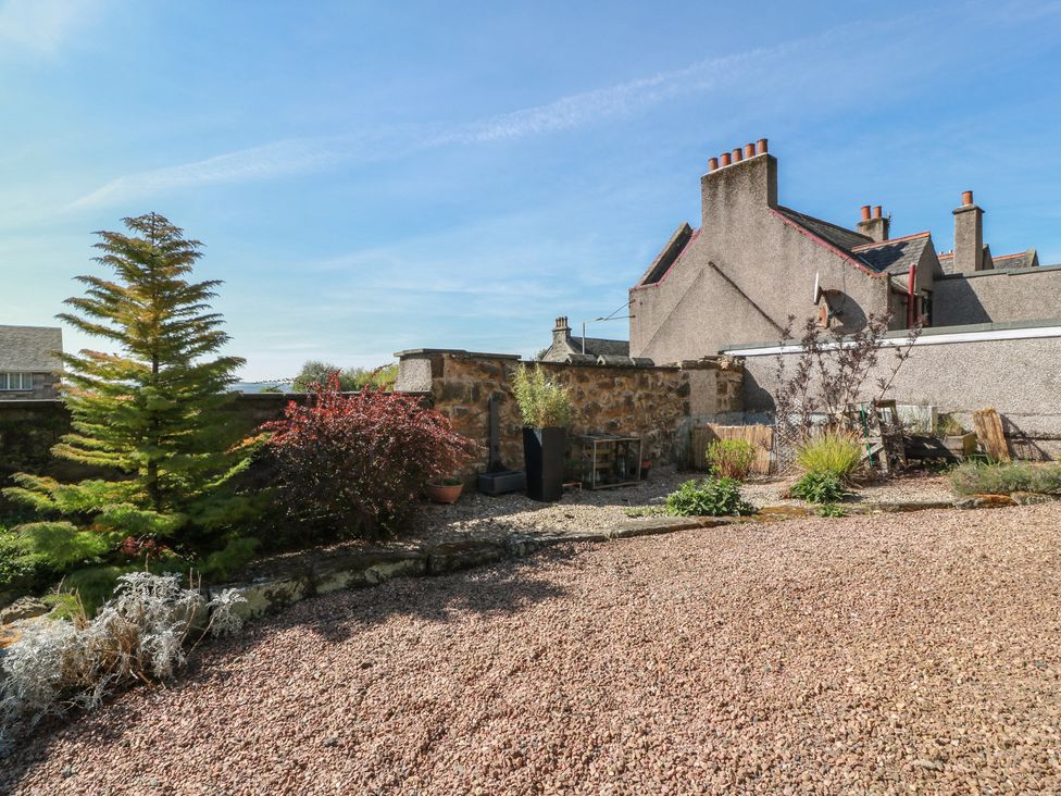 A garden with gravel, plants, and a stone wall at Crown Cottage in Newmills near Cairneyhill