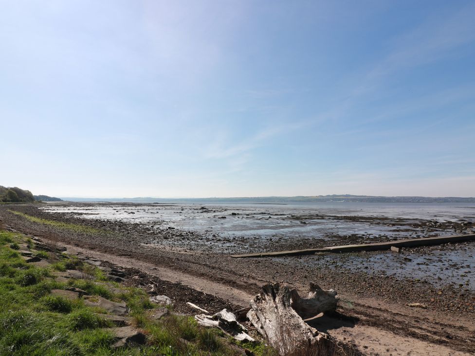 A beach with rocks and driftwood at Crown Cottage in Newmills near Cairneyhill