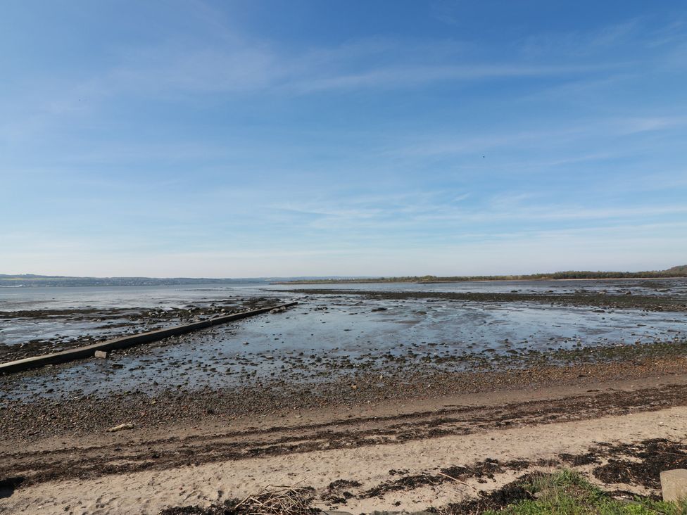 A beach with water and a pier at Crown Cottage near Newmills in Cairneyhill