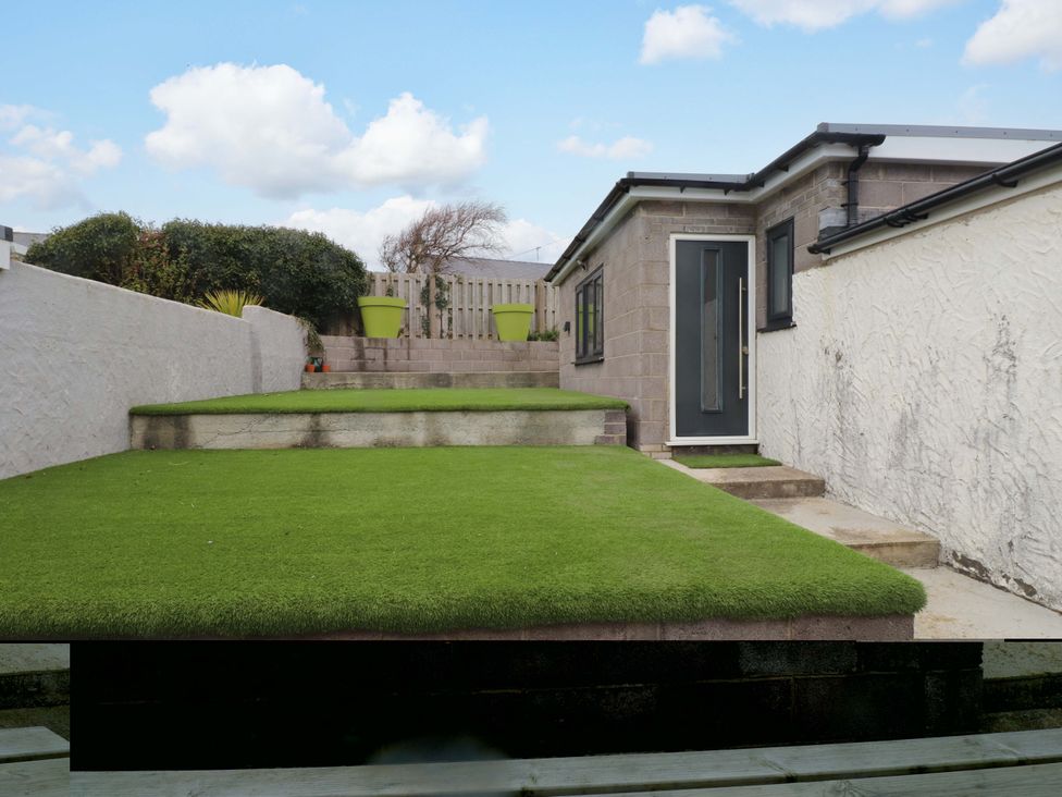 A garden area with artificial grass and potted plants at 7 Sisial Y Mor Rhosneigr