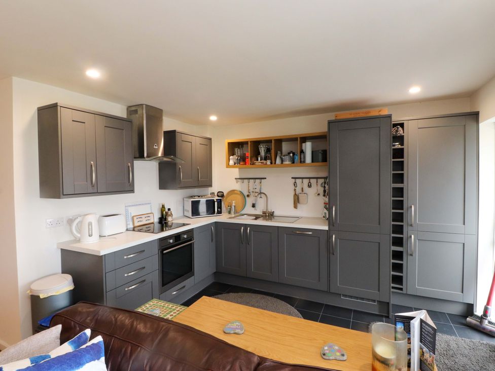 A kitchen with grey cabinets and appliances at 7 Sisial Y Mor in Rhosneigr