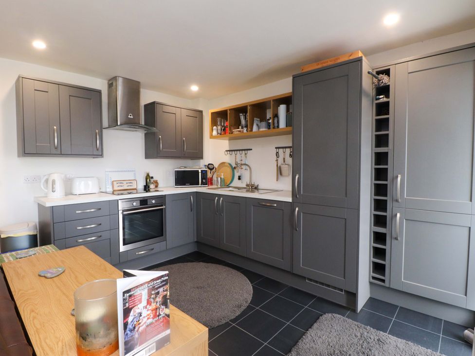 A kitchen with cabinets and appliances at 7 Sisial Y Mor in Rhosneigr