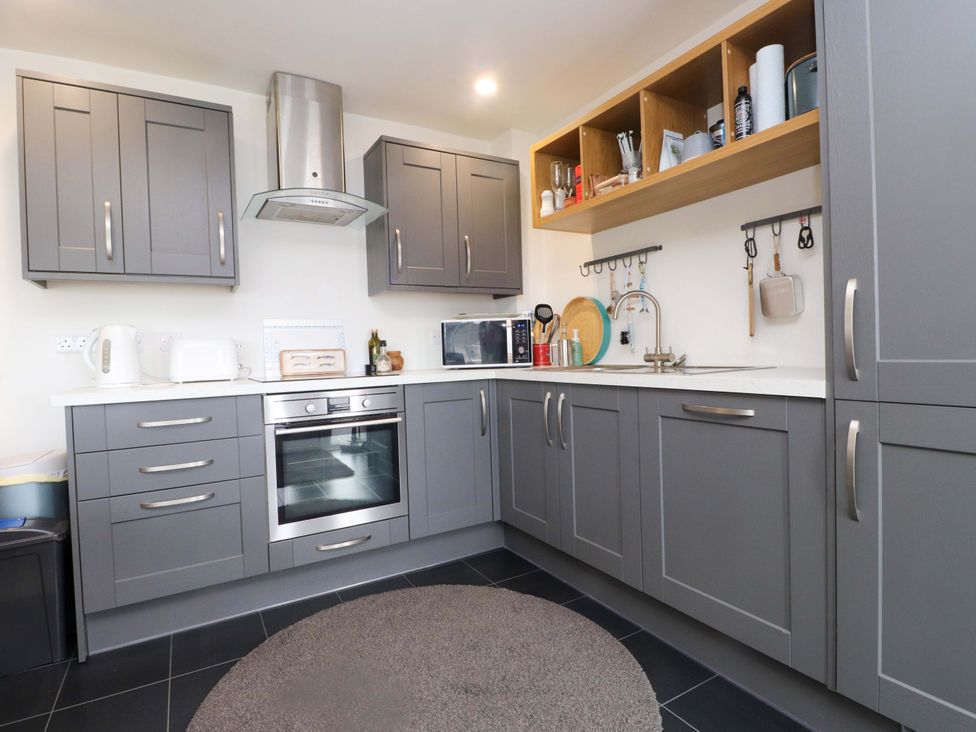 A kitchen with cabinets and appliances at 7 Sisial Y Mor Rhosneigr