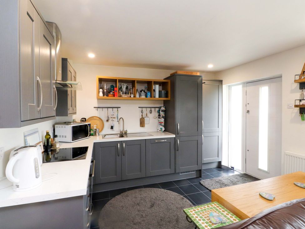 A kitchen with cabinets, sink and table at 7 Sisial Y Mor Rhosneigr