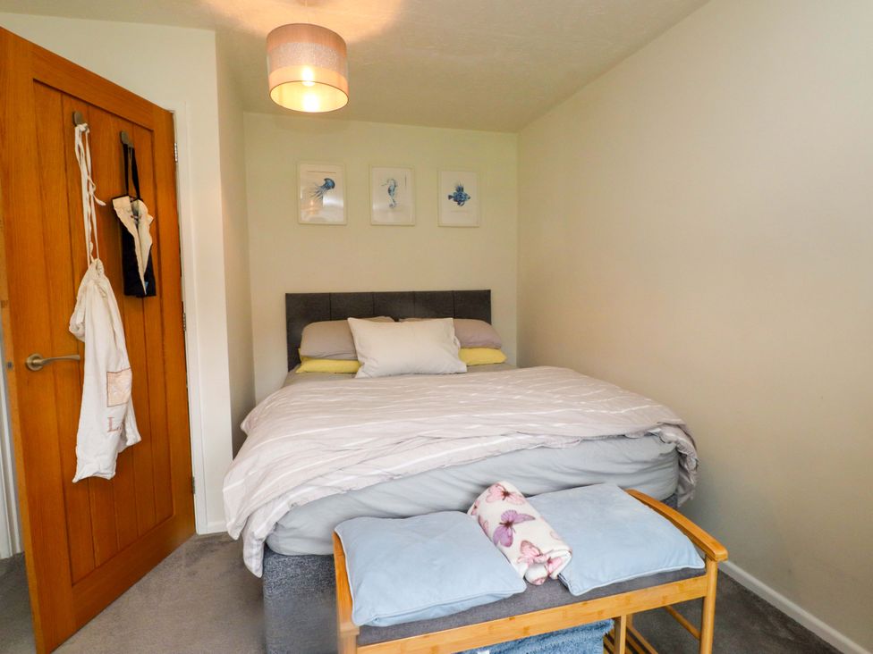 A bedroom with a bed and a bedside table at 7 Sisial Y Mor in Rhosneigr