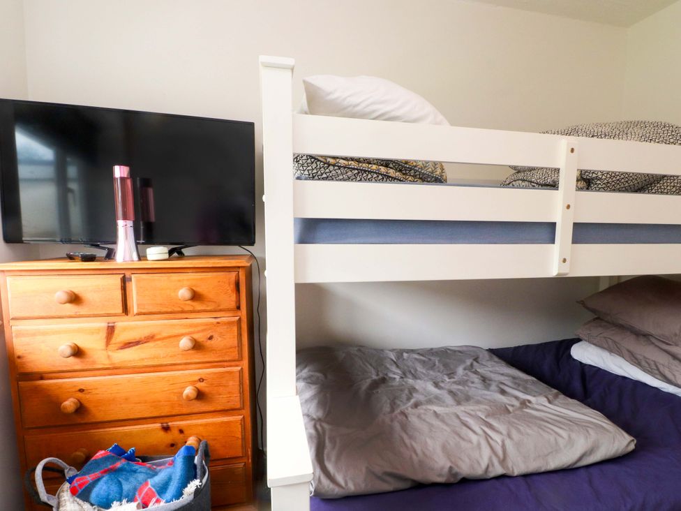 A bedroom with a bunk bed and television at 7 Sisial Y Mor Rhosneigr