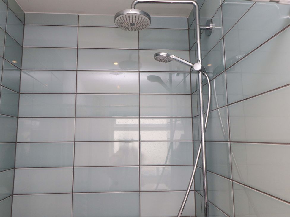 A shower area with a showerhead and tiled walls at 7 Sisial Y Mor Rhosneigr