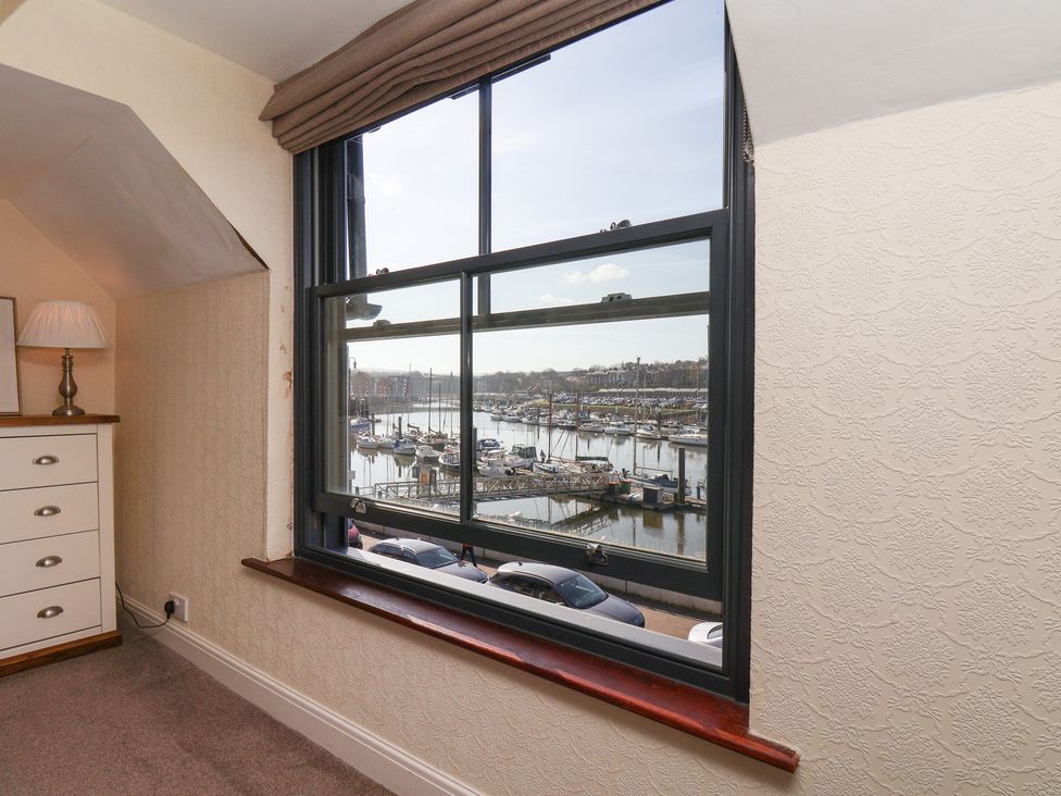 A bedroom with a window overlooking a marina at Marina House in Whitby