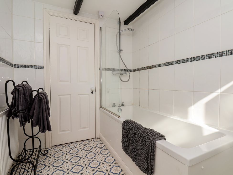 A bathroom featuring a bathtub, showerhead, and towel rack at Marina House in Whitby